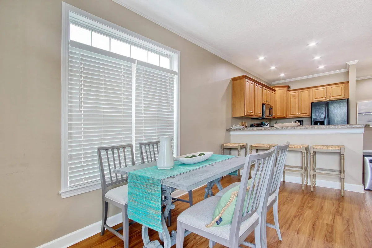 A welcoming dining area featuring a dining table adjacent to the kitchen counter, with large windows letting in natural light. The setting is ideal for family meals and social gatherings, embodying the warmth and conviviality described in the section.