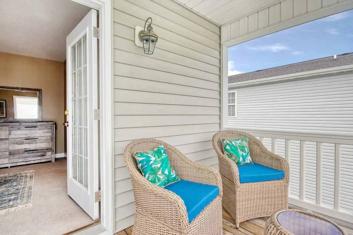 This inviting outdoor seating area features woven chairs with colorful cushions, set against a backdrop of natural greenery and open sky. The tranquil environment suggests a perfect spot for unwinding with a book, socializing with loved ones, or watching the sunset after a day of pier adventures.
